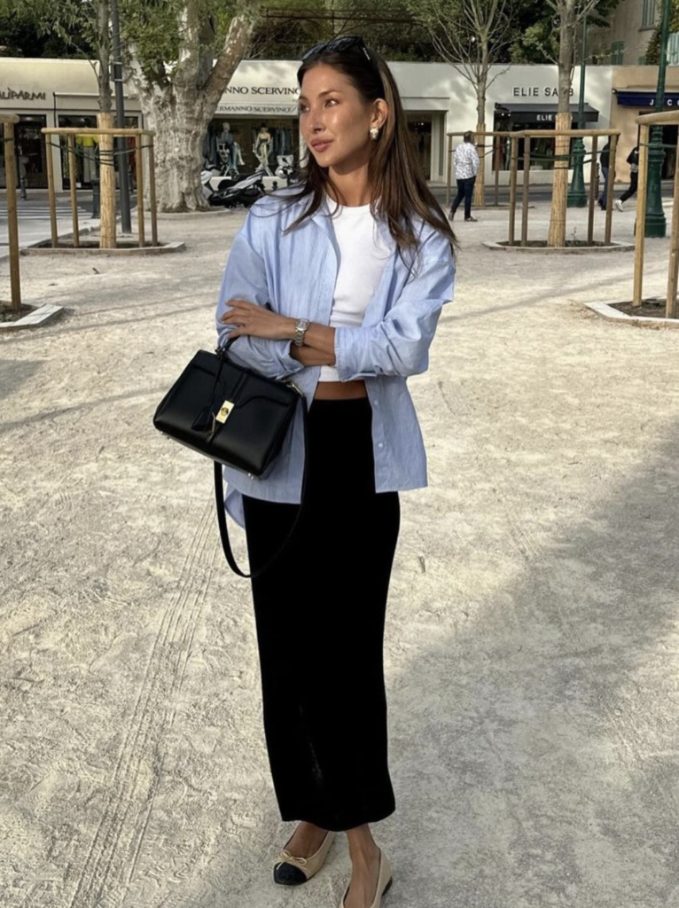 White top and black maxi skirt brunch outfit with light blue oversized shirt and black handbag.